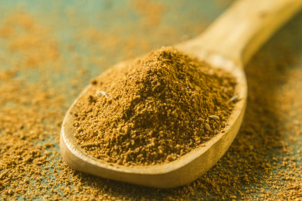 Ground cumin powder in wooden spoon.